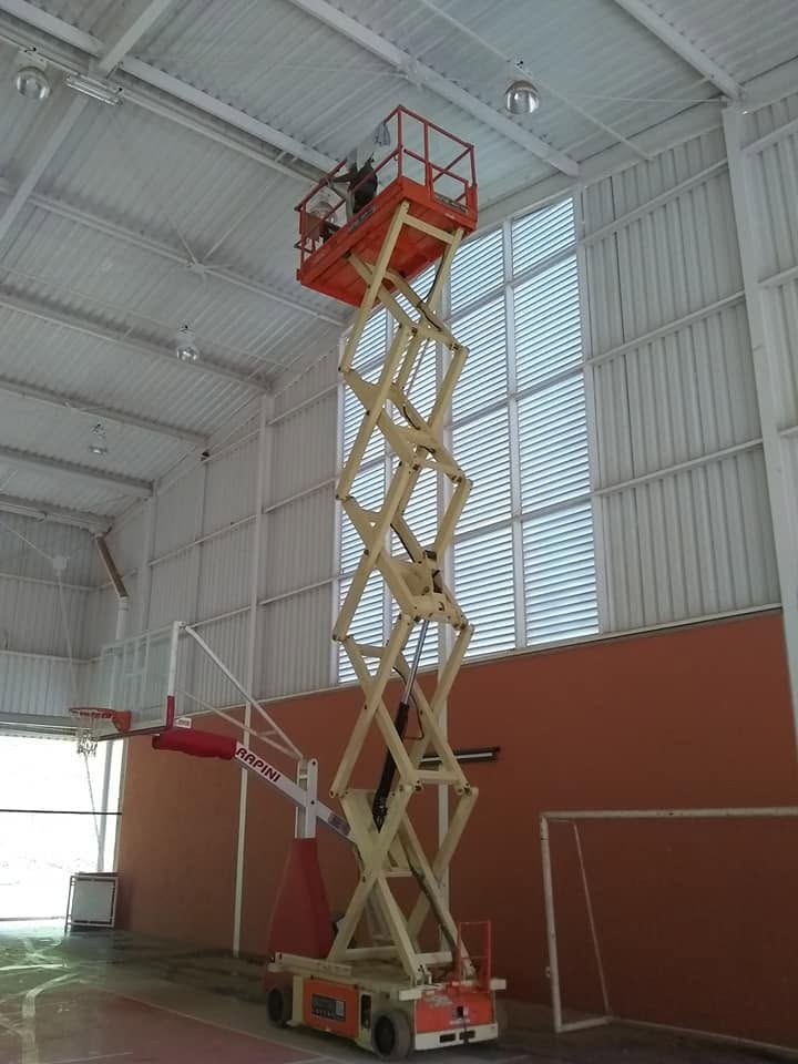 Plataforma tesoura elevada limpando a estrutura interna de um ginásio